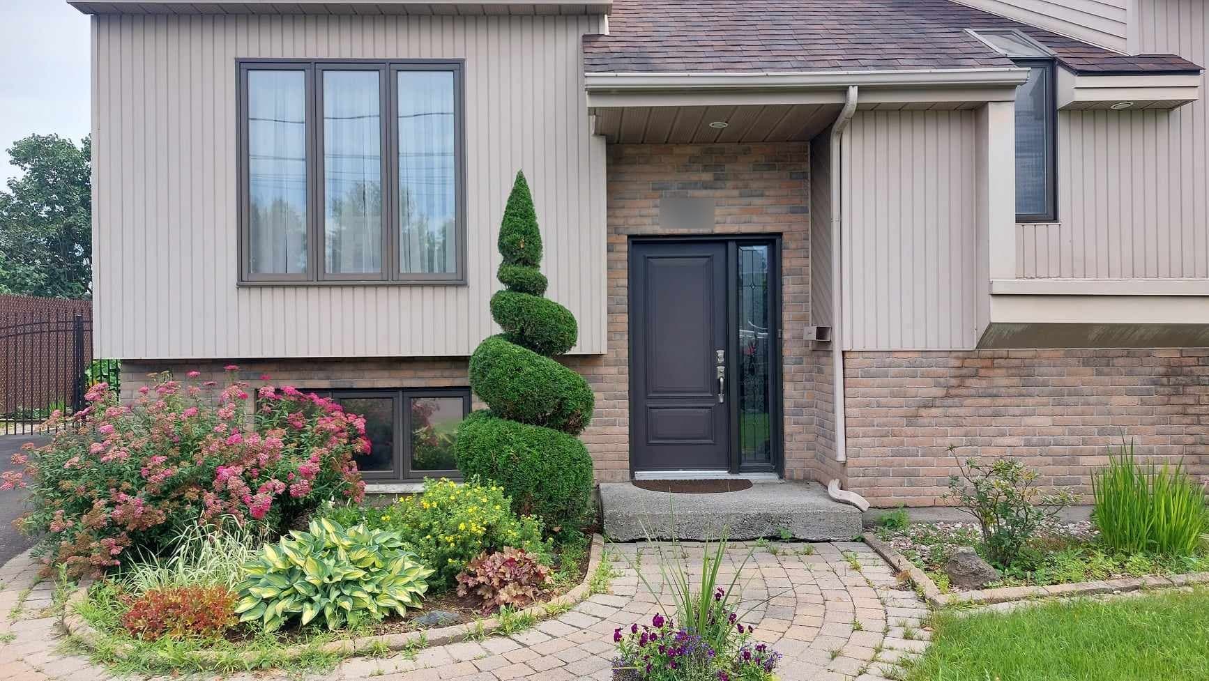 Cèdre sculpté en spirale devant une entrée de maison à Candiac